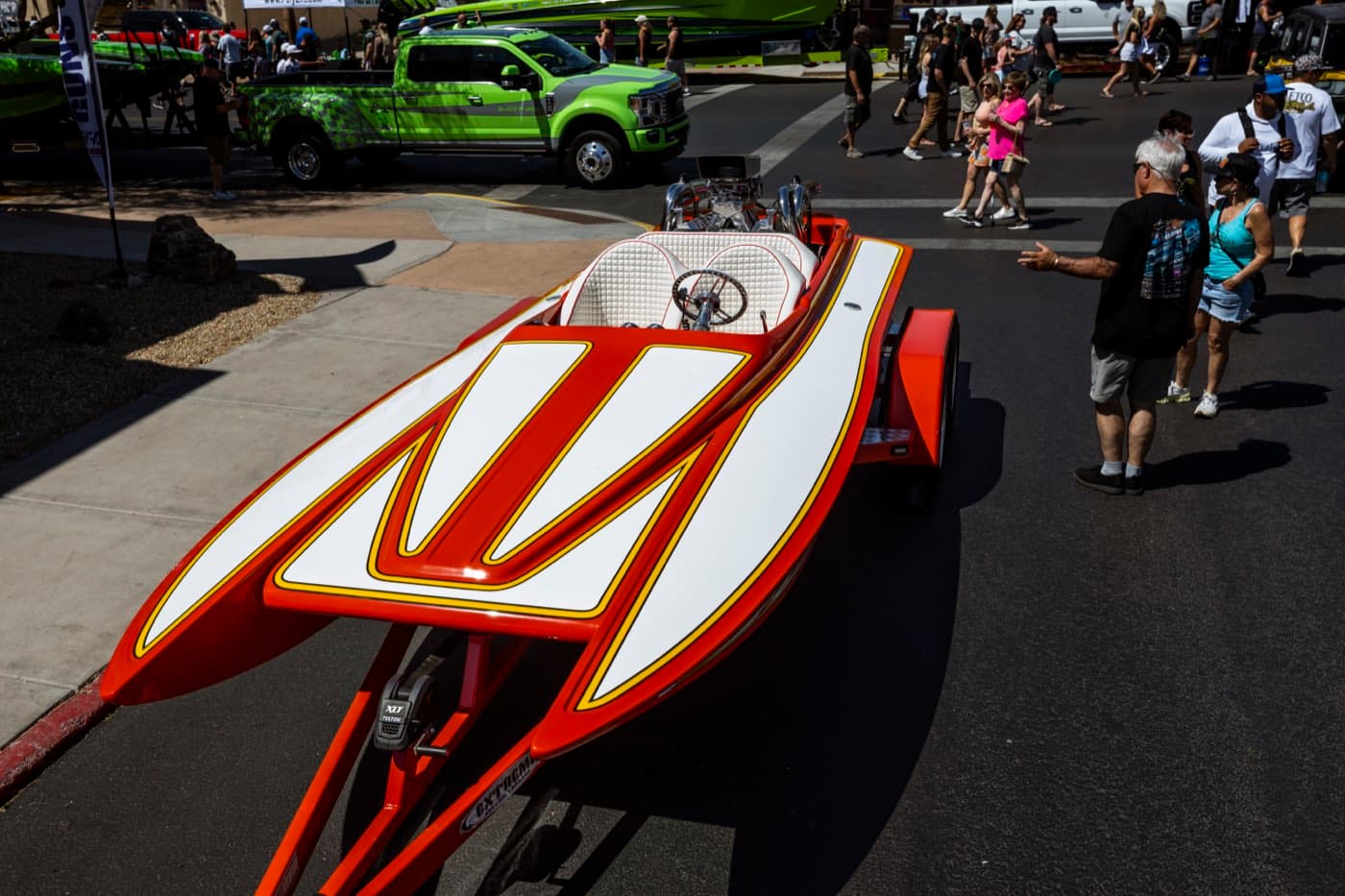 A raceboat parked on the boulevard as the crowd walks past